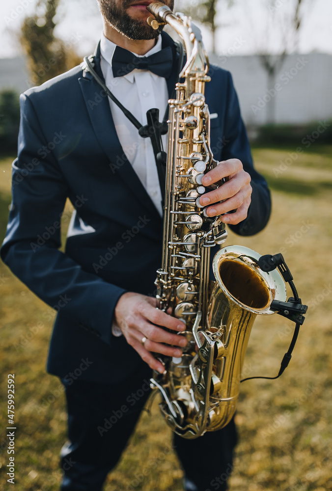 Fototapeta premium Stylish man in suit, musician, professional saxophonist in suit plays the saxophone.
