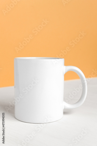 White ceramic cup with copy space front view. Drink mug with empty space, mockup, template for design and logo close-up on colored background.