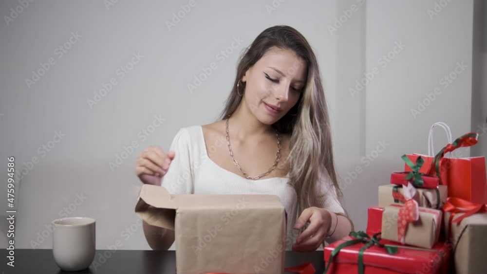 Curious young woman opening her presents for the New Year's Eve Curious young woman opening her presents for the New Year's Eve