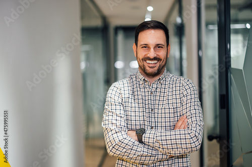 Portrait of cheerful adult man, standing in the halls of his firm. photo