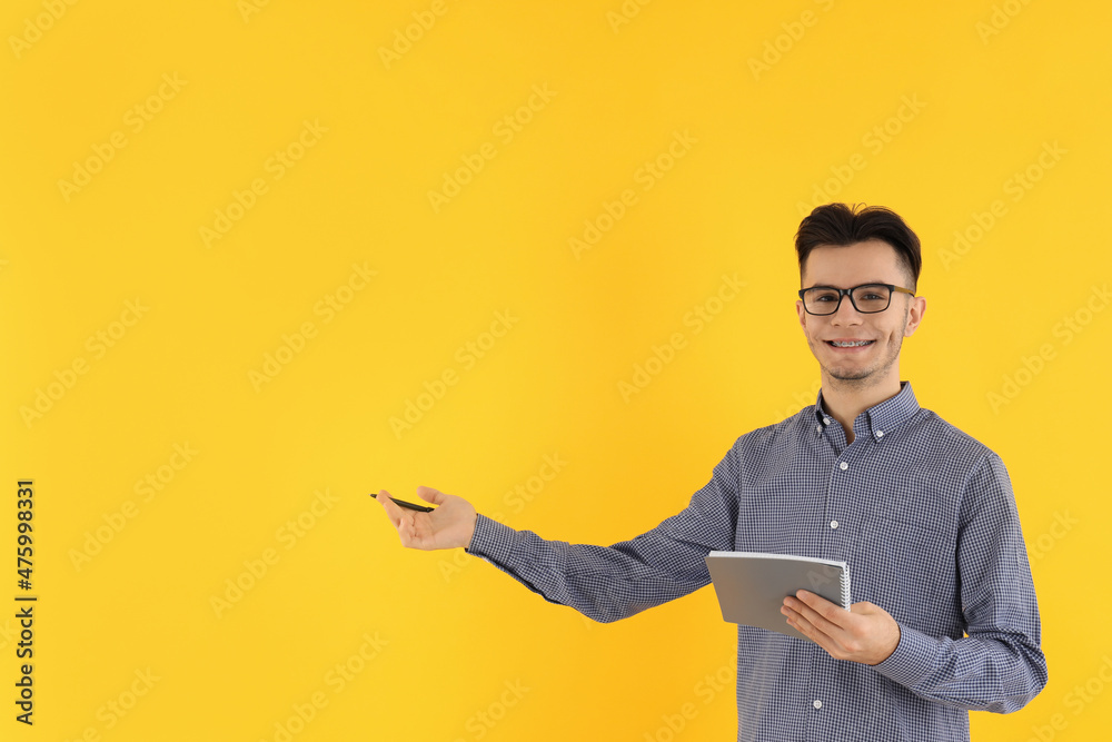 Attractive guy with notebook and pen on yellow background Attractive guy with notebook and pen on yellow background