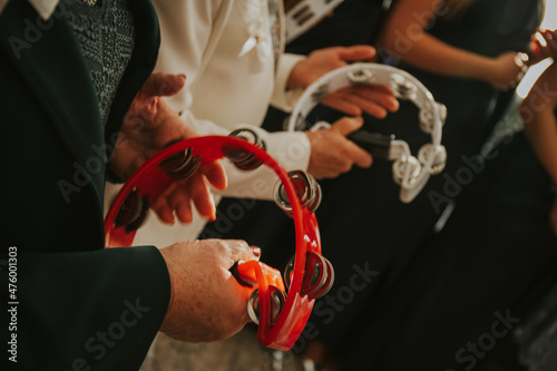Fototapeta Closeup shot of two people sitting with tambourines in their hands at a wedding
