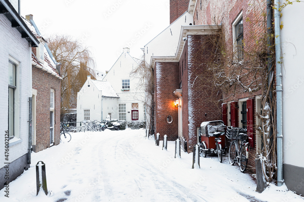 Naklejka premium A wintry cityscape of the medieval city of Amersfoort in the center of the Netherlands. Buildings and streets are covered with snow. 