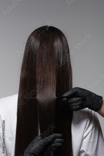 Obraz na plátne back view of woman with smooth long hair near colorist in latex gloves isolated