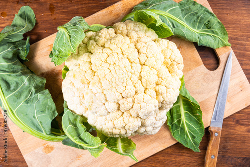 Cauliflower on a kitchen wooden cutting board, top view, close-up