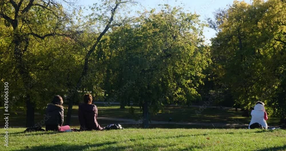 People are resting in the park in nature. Sit on the lawn and talk. Autumn weather People are resting in the park in nature. Sit on the lawn and talk. Autumn weather