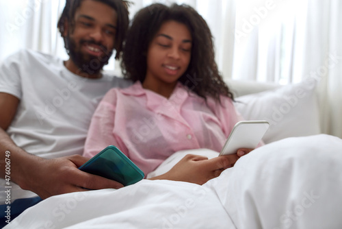 Blur of black couple watching on smartphone on bed