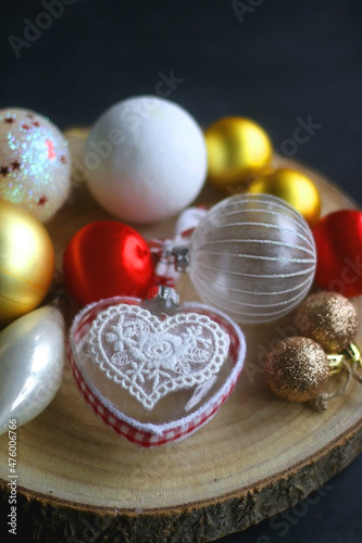Wooden tray with Christmas ornaments in red, gold and white tones. Dark background, selective focus.