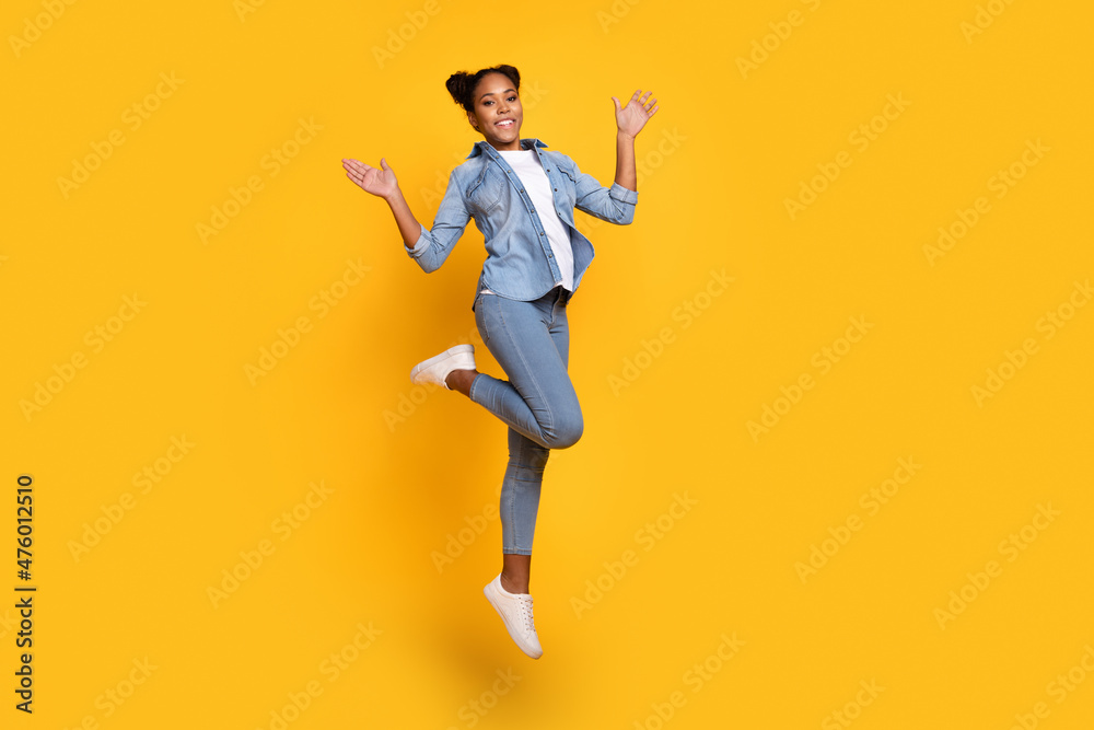 Full body profile side photo of young african girl jump excited wear casual outfit wave hello isolated over yellow color background
