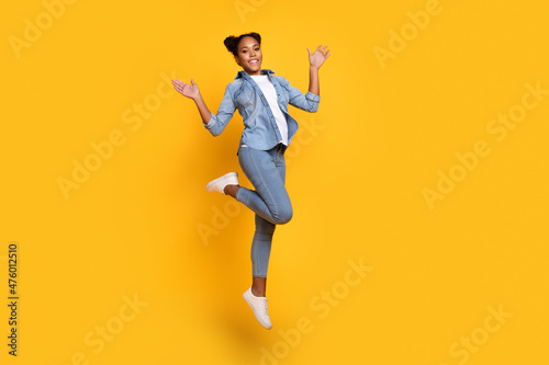 Full body profile side photo of young african girl jump excited wear casual outfit wave hello isolated over yellow color background