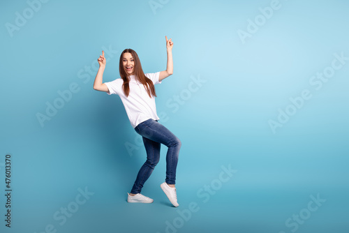 Full body photo of young lovely lady indicate fingers empty space promo dancing isolated over blue color background