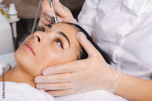 Cosmetologist hands making the procedure Microdermabrasion of the facial skin of a client at the spa salon. Facial skin treatment. Rejuvenation treatment. Skin photo