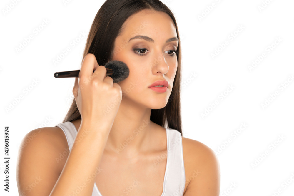 a young beautiful woman is applying powder with a makeup brush