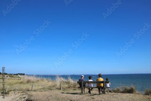 famille assise sur un banc face à la mer