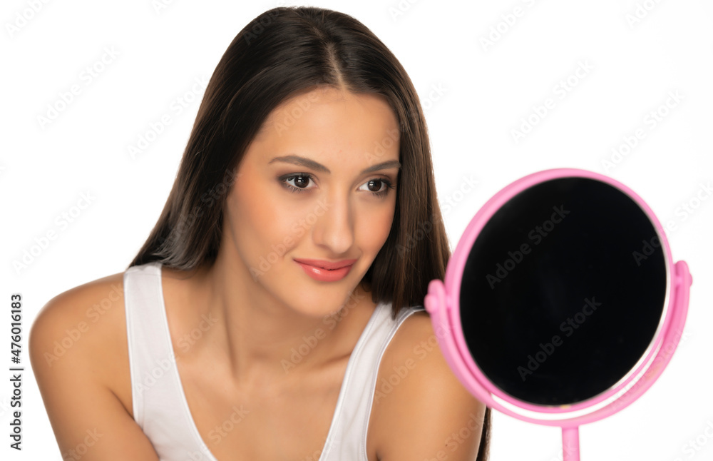 portrait of a young satisfied woman with long black hair, look at her self in the mirror portrait of a young satisfied woman with long black hair, look at her self in the mirror