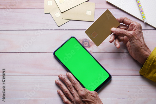 senior women hand holding credit card and using smart phone shopping online 