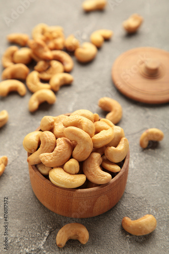 Cashew nuts on wooden bowl on grey background. Top view.