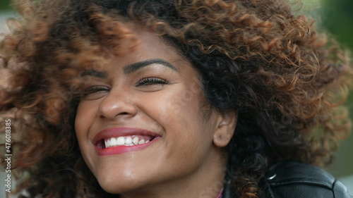 Carefree latina black woman shaking hair and smiling at camera © Marco