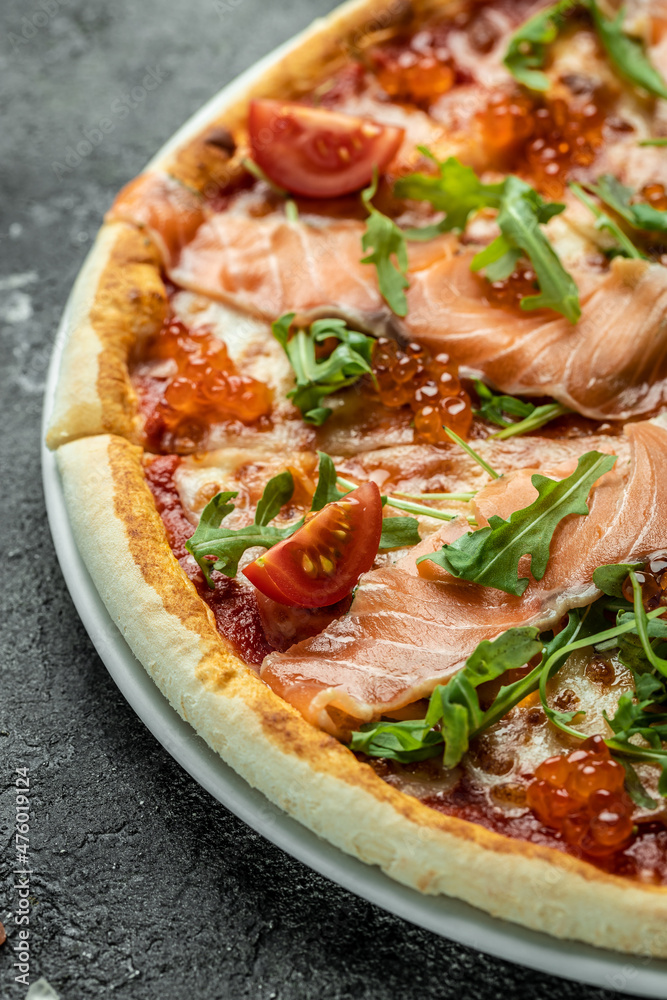 Pizza with salmon, red caviar, tomatoes and aragula. Traditional italian cuisine. vertical image. top view. place for text