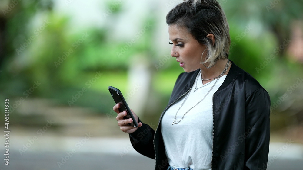 Annoyed woman reacting negatively to news on cellphone device outside