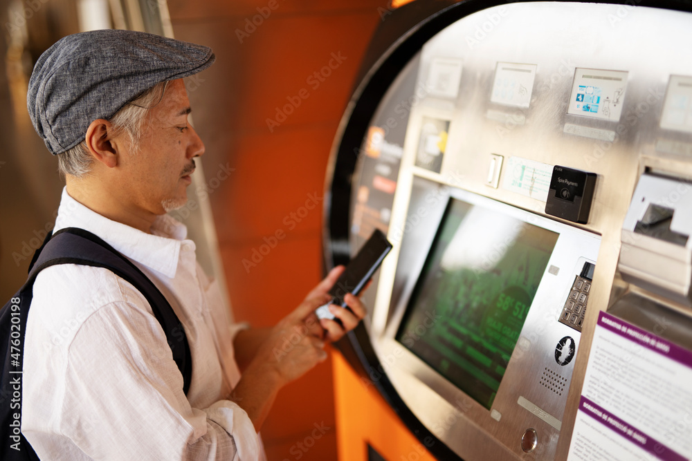 Senior man withdrawing money from credit card. Man typing pin code on keypad of ATM mashine...