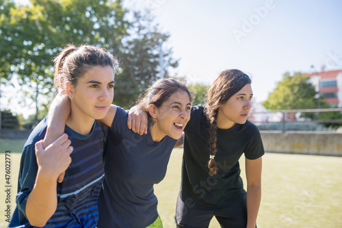 Young female friends on football field. Sportswomen in different uniforms looking at competitives, making faces. Sport, leisure, active lifestyle concept