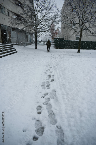 Person walking and leaving footsteps in the snow behind him while it is snowing
