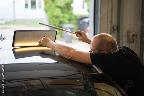 Process of Repairing Dents On Car Body. Technician Is Working Using Professional Tools For Paintless Dent Repair. Man Is Repairing Dents On Car Roof After Hail. PDR Removal Course