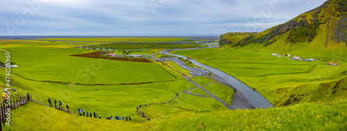 Panoramic view over staircase to the top of the famous Icelandic Skogafoss waterfall, with tourists while hiking in Iceland, summer, and camping site at the waterfall base. photo