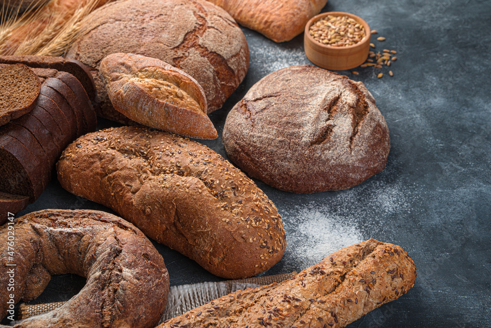Assortment of rye and wheat bread on a dark background with flour.