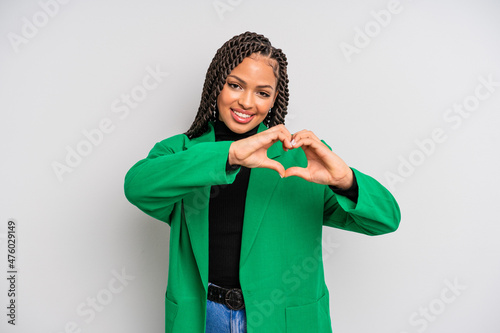 black afro woman smiling and feeling happy, cute, romantic and in love, making heart shape with both hands photo