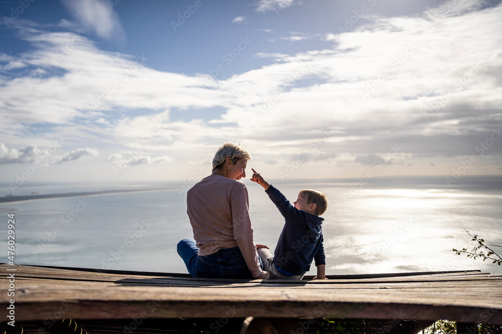 Mother and 3 years old son talking to each other having the beautiful ocean view.iew,