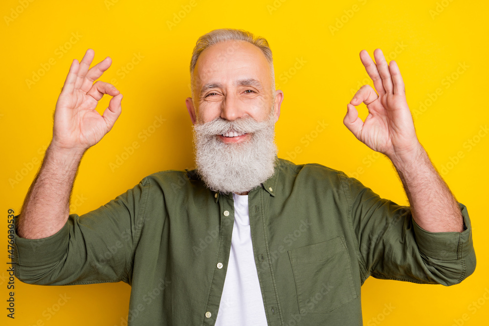 Photo portrait of elder man smiling showing okay gesture isolated vivid yellow color background Photo portrait of elder man smiling showing okay gesture isolated vivid yellow color background