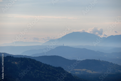 A panoramic view on endless mountain chains in Carinthia, Austrian Alps. The mountains are shrouded in fog. In the distance you can see the viewing tower Pyramidenkogel. Serenity and calmness photo