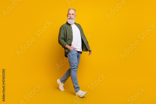 Full length body size photo of positive happy senior man smiling going forward isolated bright yellow color background