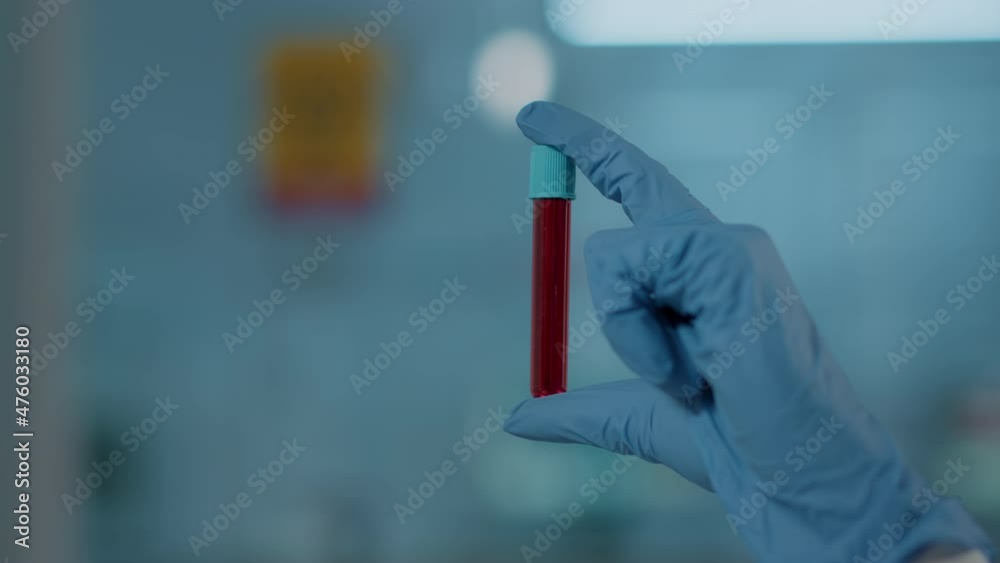 Hand with gloves holding test tube in science laboratory, analyzing dna substance for biology experiment. Microbiology specialist working with glassware and red liquid in flask. Close up Hand with gloves holding test tube in science laboratory, analyzing dna substance for biology experiment. Microbiology specialist working with glassware and red liquid in flask. Close up