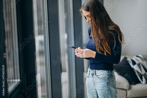 young woman typing phone keyboard by the window Free Download young woman typing phone keyboard by the window - GFXLoad