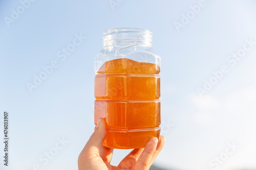 A woman’s hand holding a jar of honey