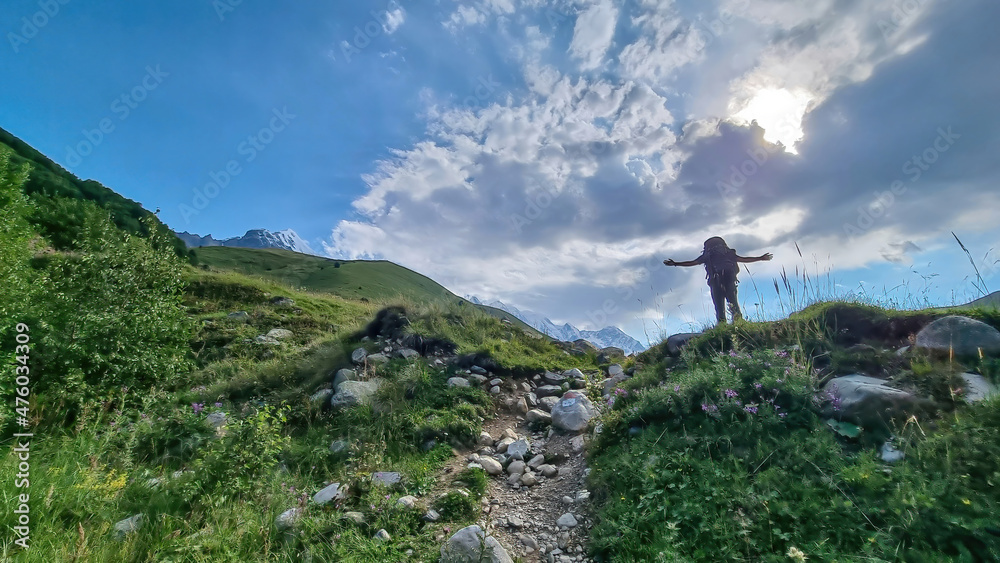 A man enjoying the panoramic view on the snow-capped peaks of Tetnuldi, Gistola and Lakutsia in the Greater Caucasus Mountain Range in Georgia, Svaneti Region. Wanderlust, solitude, hiking trail.