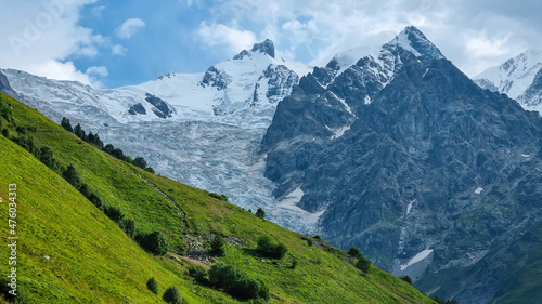 A panoramic view on the snow-capped peak of Jangi-Tau(Dzhangi-Tau) in the Greater Caucasus Mountain Range in Georgia, Svaneti Region. Hills with lush pastures, sharp peaks, hiking vibes.