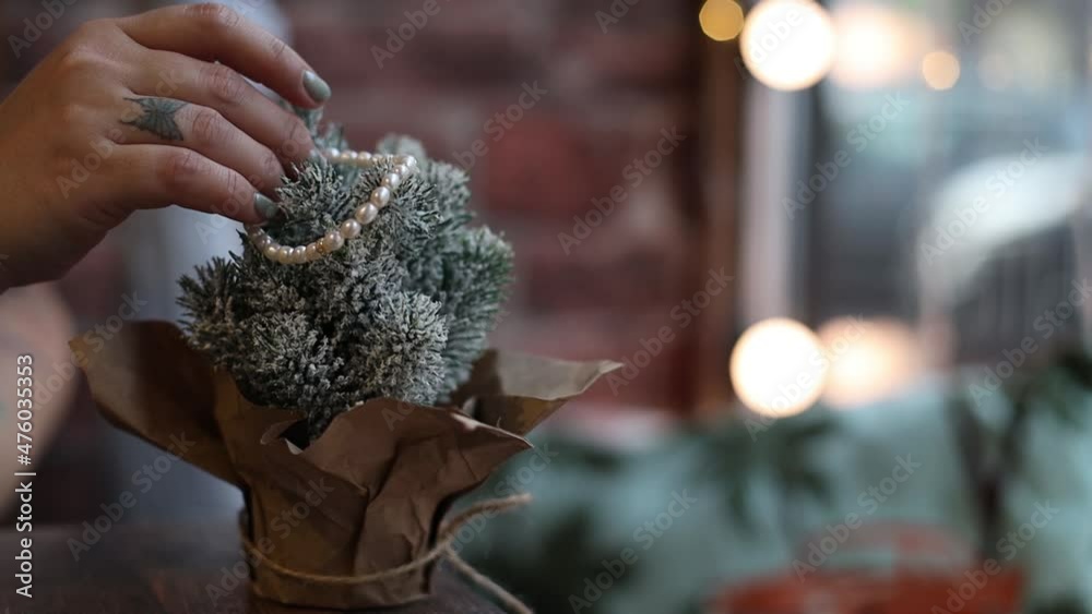 woman decorates a decorative Christmas tree standing on the table at home woman decorates a decorative Christmas tree standing on the table at home