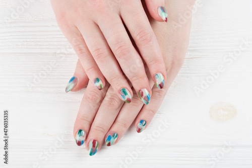 Female hands with stylish manicure closeup. Colorful nail art on wooden background.