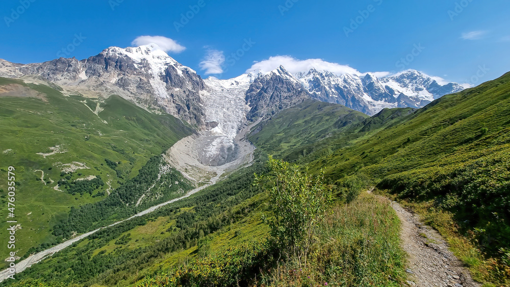 A hiking/trekking trail with a panoramic view on the snow-capped peaks of Tetnuldi, Gistola, Lakutsia and the Adishi Glacier in the Greater Caucasus Mountain Range in Georgia,Svaneti Region.Wanderlust