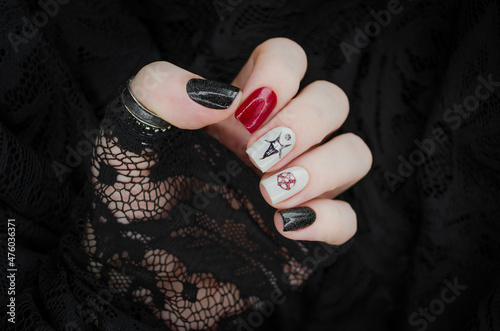 Black and red gothic manicure with mystic nail art. Creative nail concept on black lace background.