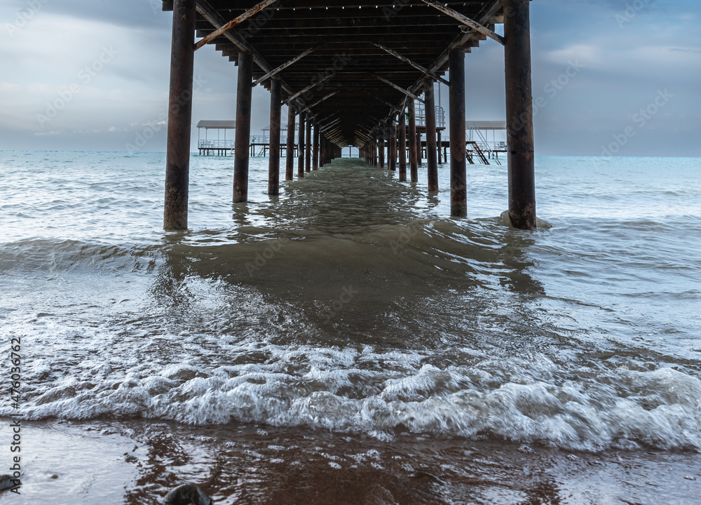 cloudy day at sea. waves under the pier