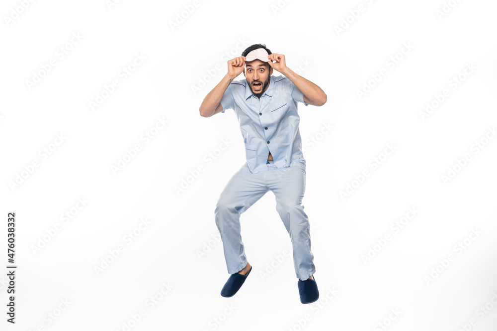 amazed man in pajamas and sleeping mask levitating on white. amazed man in pajamas and sleeping mask levitating on white.
