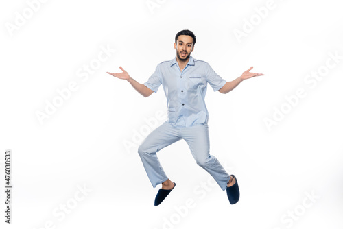 bearded man in pajamas levitating while gesturing on white.