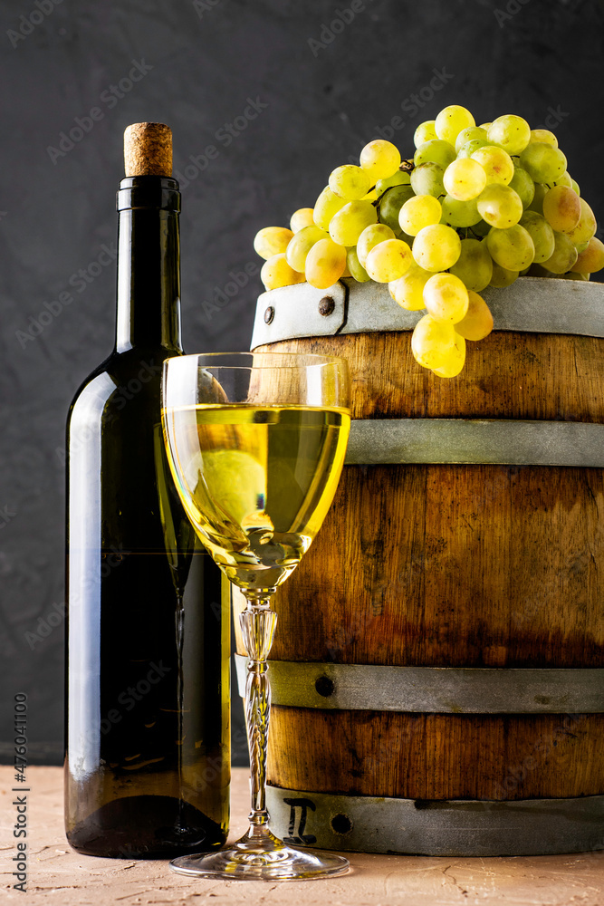 Φωτογραφία a bottle of wine a glass an oak barrel and a bunch of white grapes on a dark bac