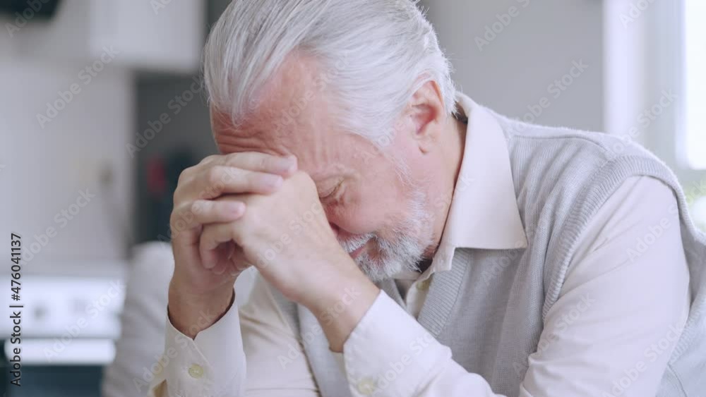 Unhappy senior man sitting in room alone, crying upset with problem, loneliness