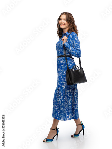 fashion, style and people concept - happy smiling beautiful young woman posing in blue dress walking over white background